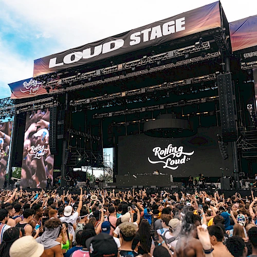 The image shows a large outdoor music festival stage labeled "LOUD STAGE" with a crowd gathered, featuring "Rolling Loud" branding.