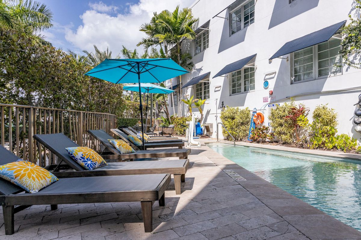 A poolside area with lounge chairs, umbrellas, and a building in the background.